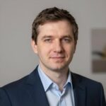 Портрет уверенного российского бизнесмена с дружелюбным взглядом на нейтральном размытом фоне студии