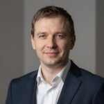 Портрет уверенного российского бизнесмена с дружелюбным взглядом на нейтральном размытом фоне в студии