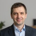 Портрет уверенного российского бизнесмена с дружелюбным взглядом на размытом нейтральном фоне в студии